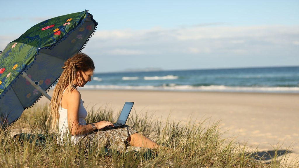 woman working on beach digital nomad