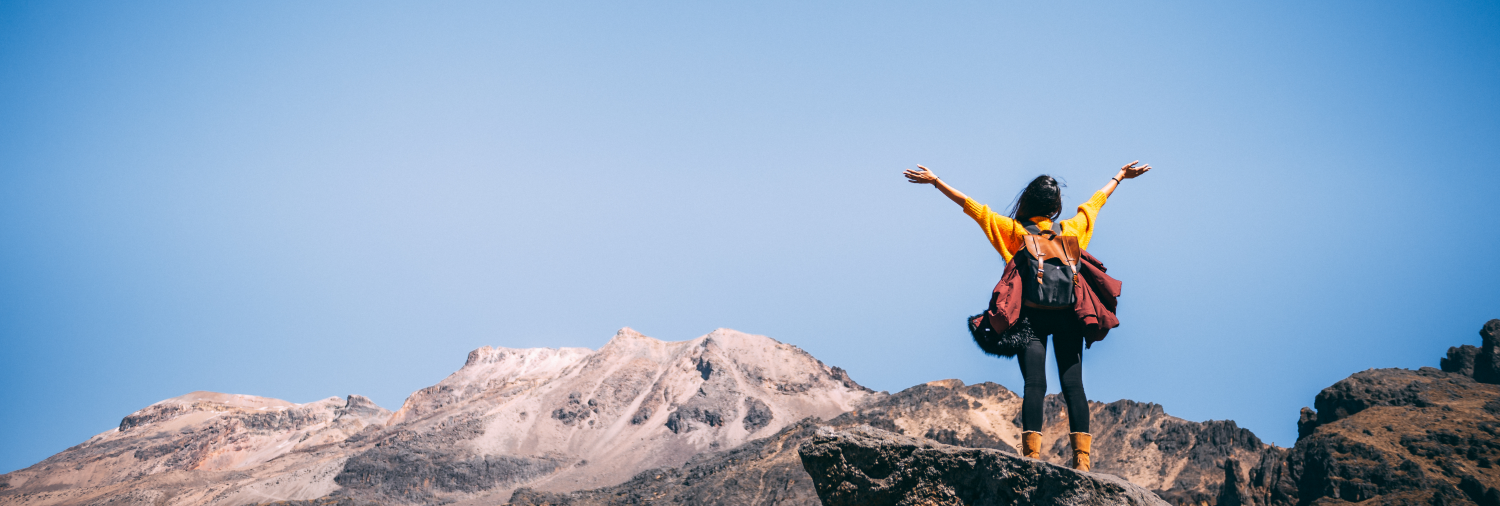 woman achieving a dream on top of a mountain